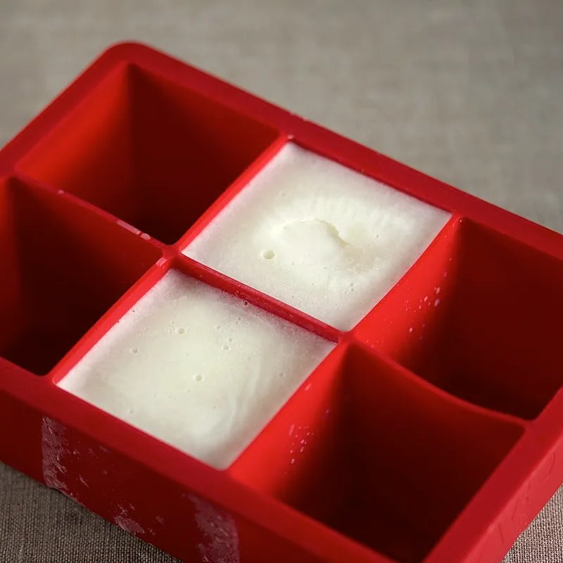 White solid vegetable shortening set into cube shapes in a red silicone tray