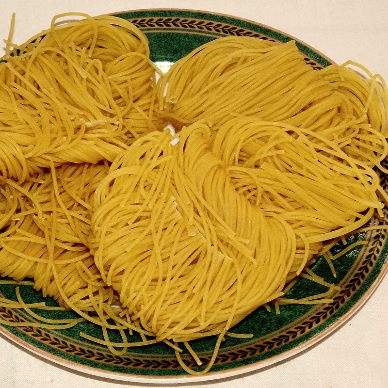 Coiled nests of dried yellow wheat vermicelli noodles on a plate