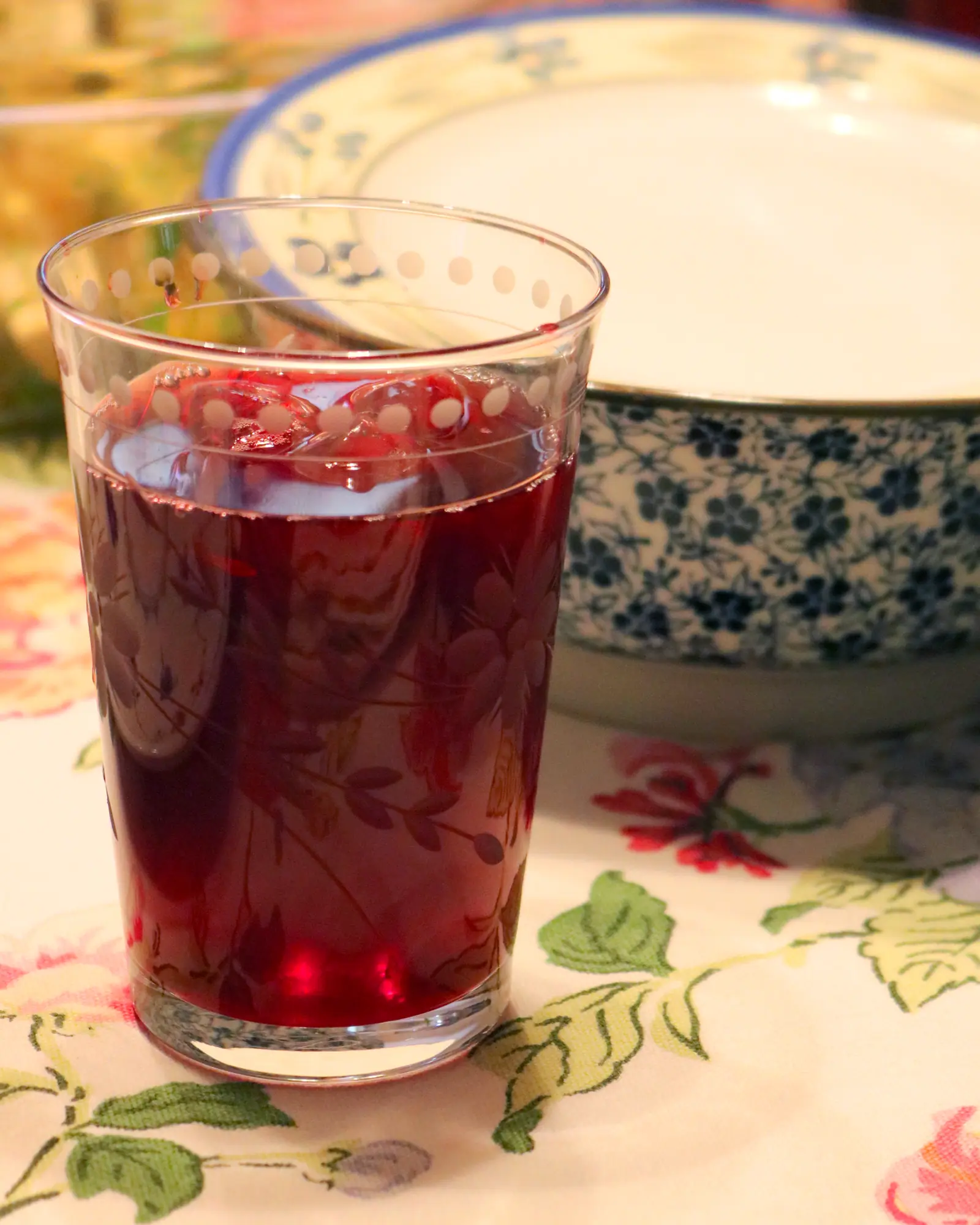 A tall glass of deep red hibiscus tea over ice, condensation on the glass
