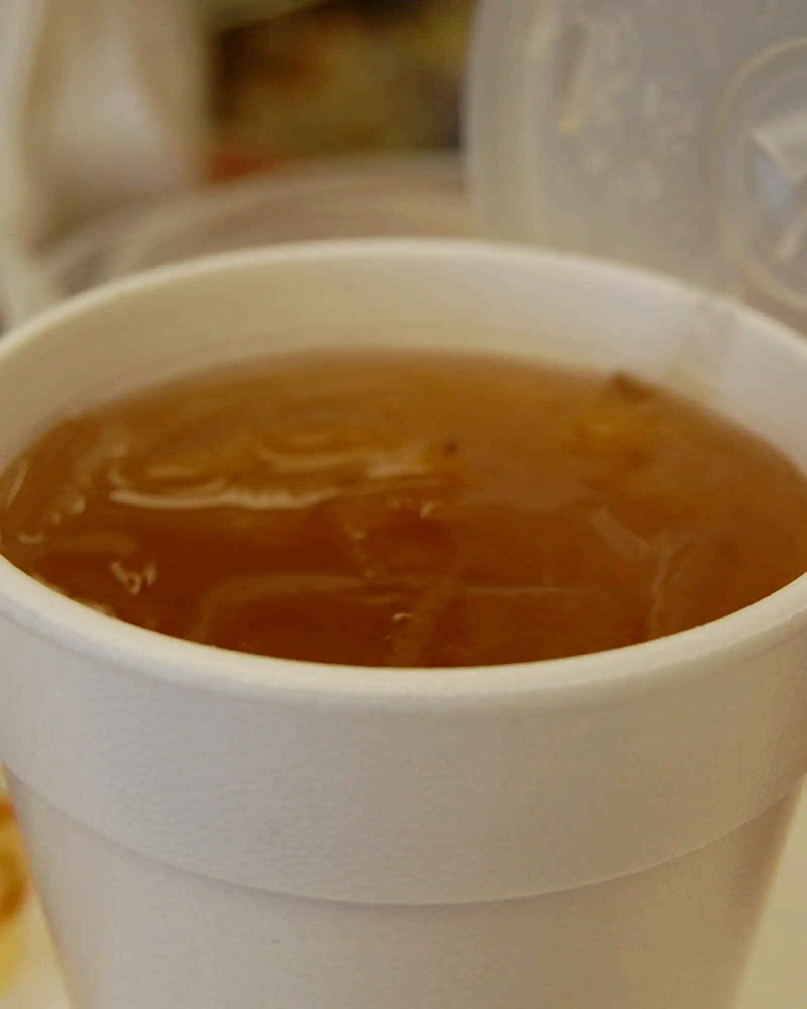 Agua de tamarindo, a translucent brown tamarind water over ice, filled to the brim of a foam cup