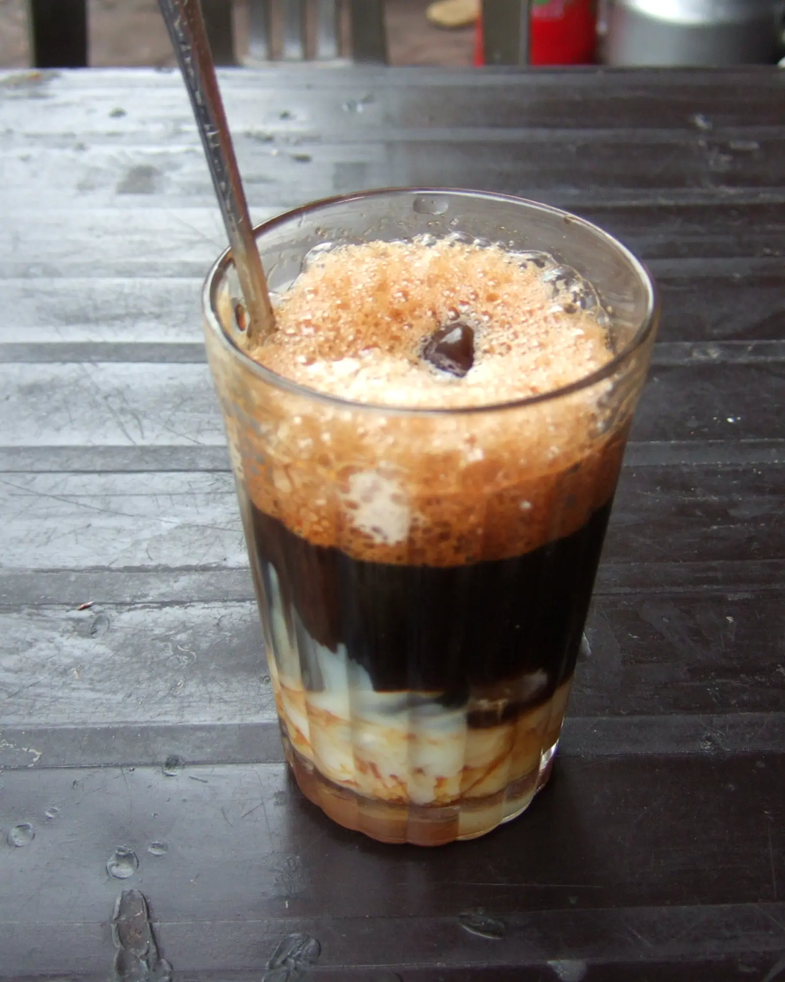 Vietnamese iced coffee in a glass, dark coffee layered over condensed milk and ice