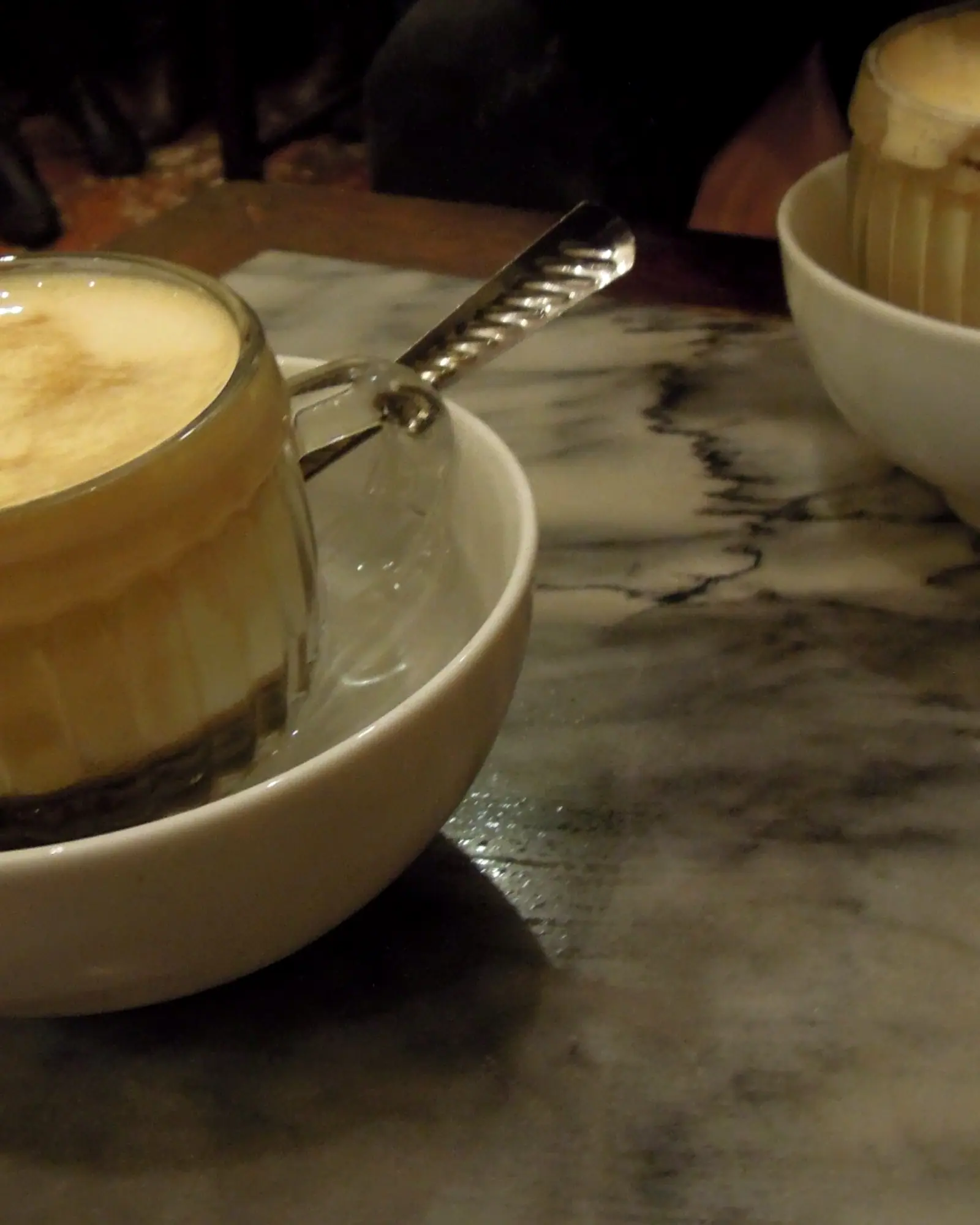 A small glass of Vietnamese egg coffee with a whipped, pale foam top, set in a bowl of hot water