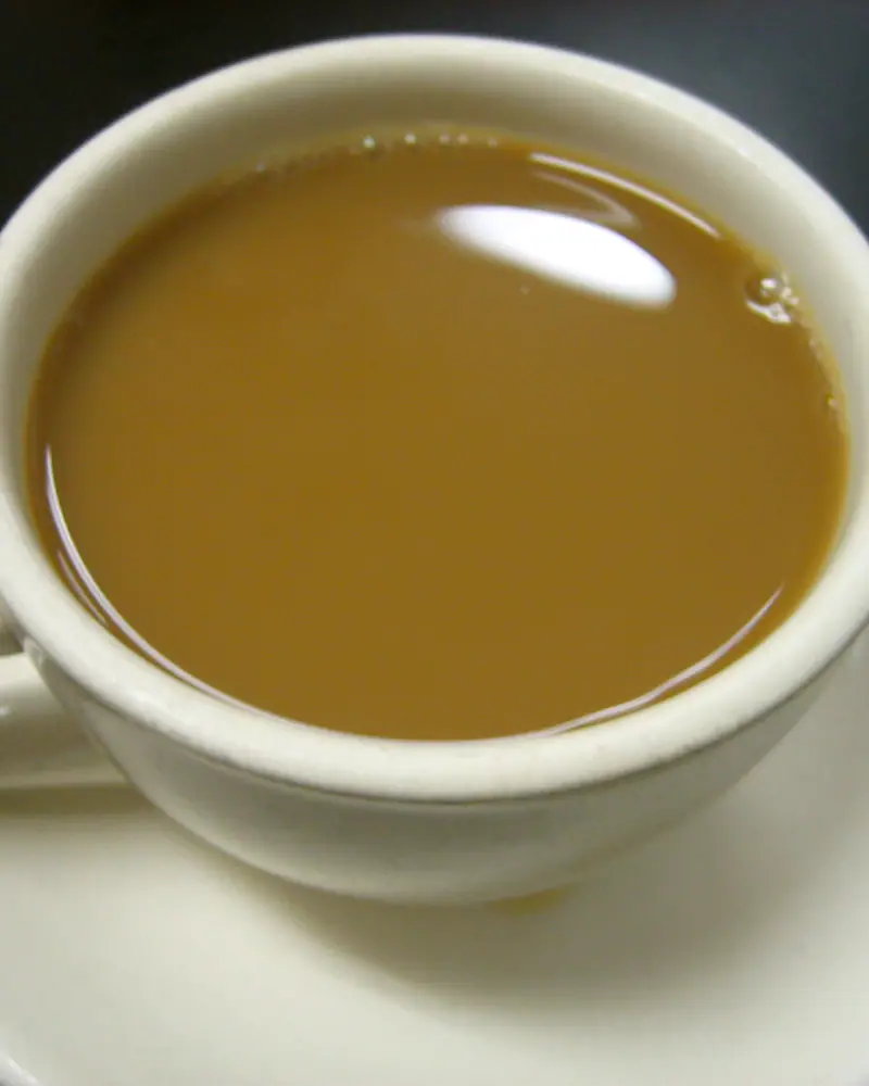 Milky coffee filling a wide white cup, viewed from above