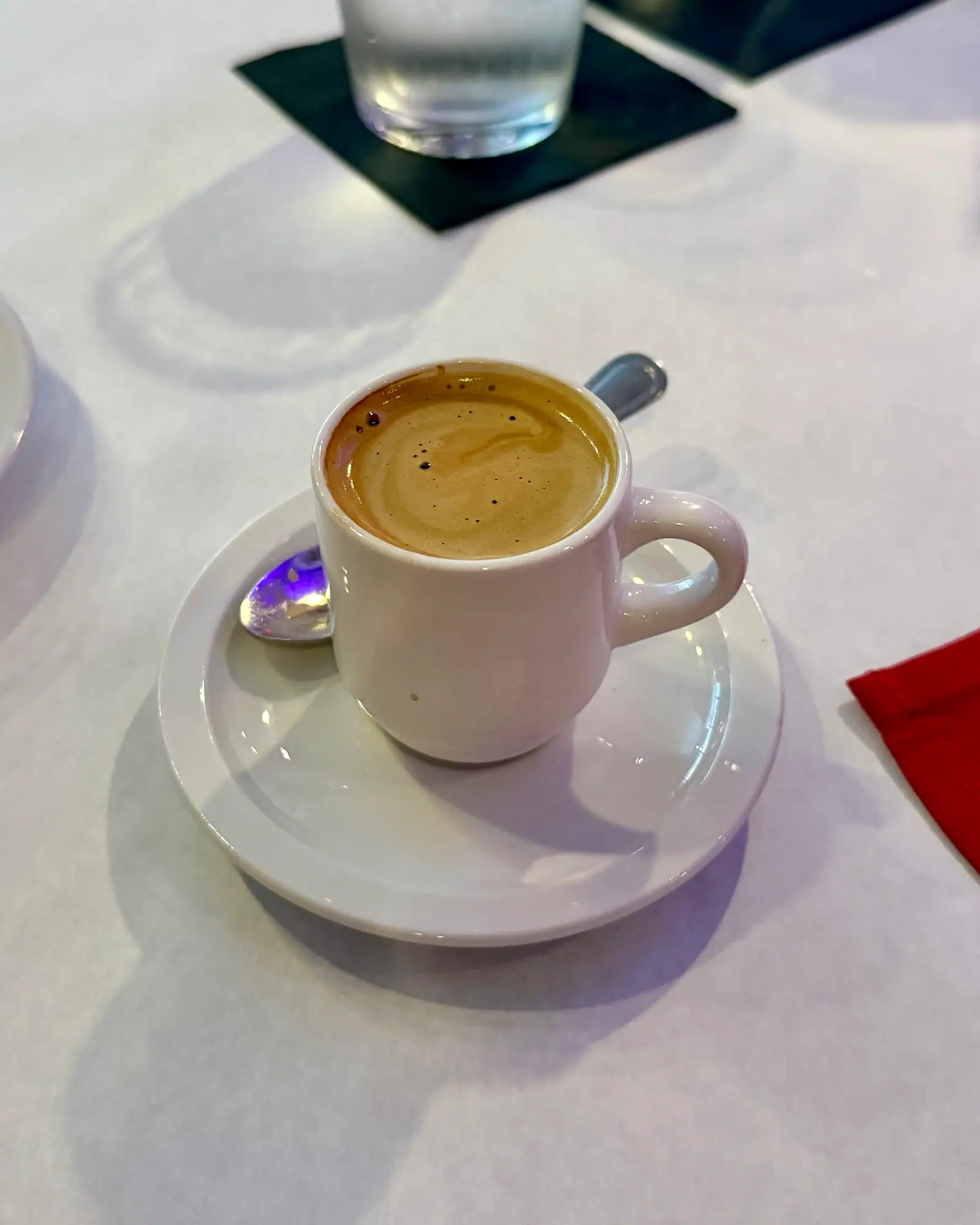 Cuban espresso topped with golden crema, in a small white cup on a saucer