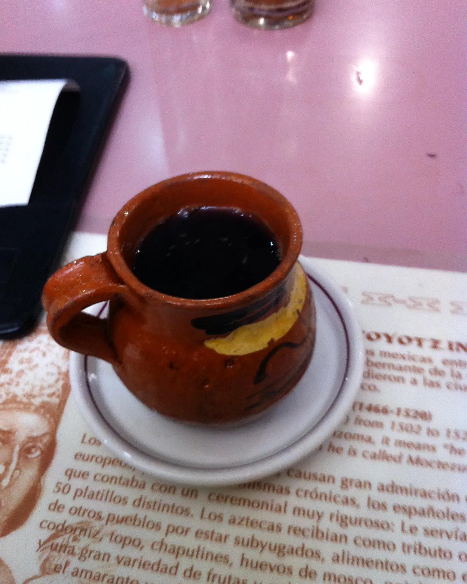 Dark cinnamon-spiced coffee in a traditional clay mug, a lemon wedge on the saucer