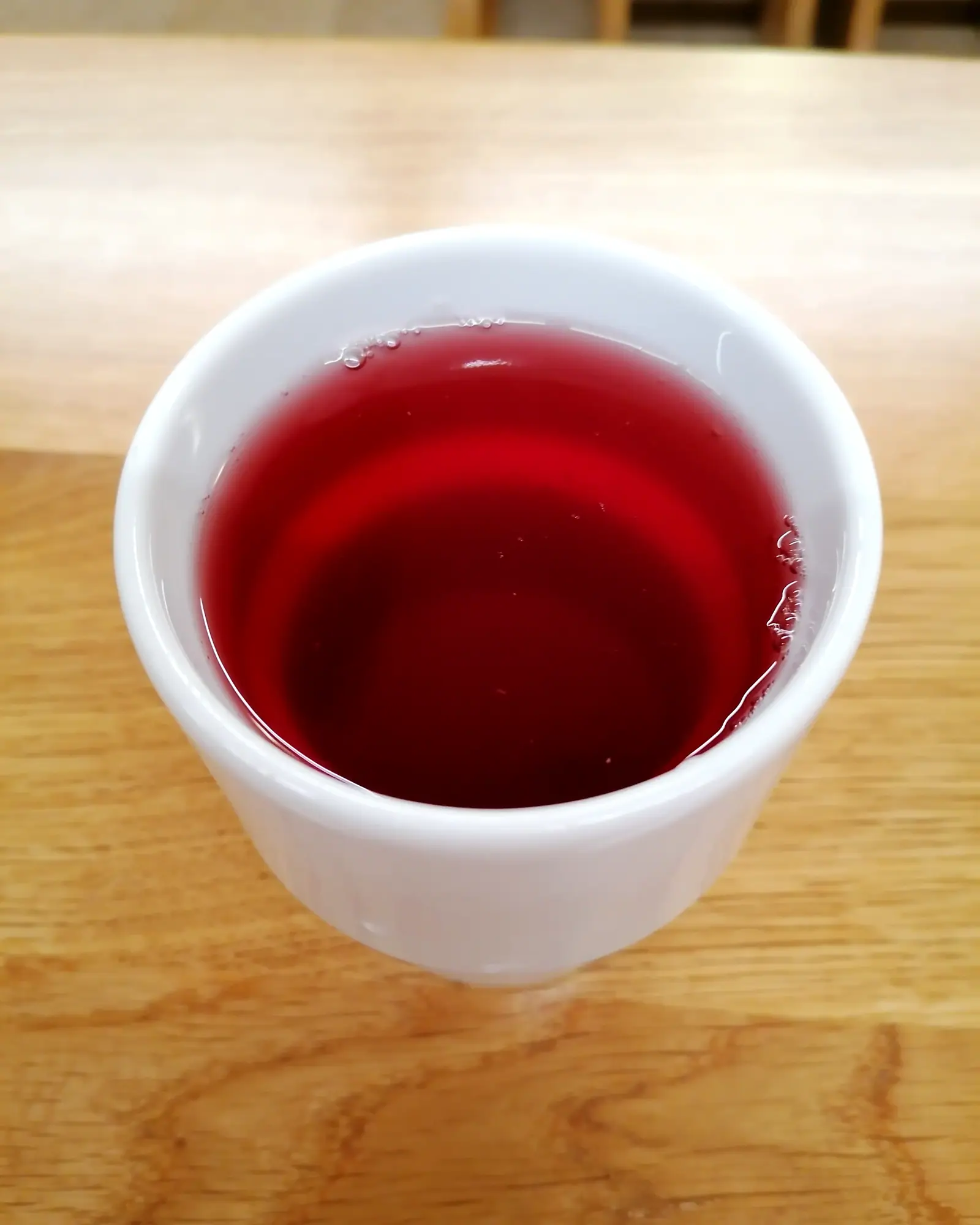 Deep red kompot filling a small white cup