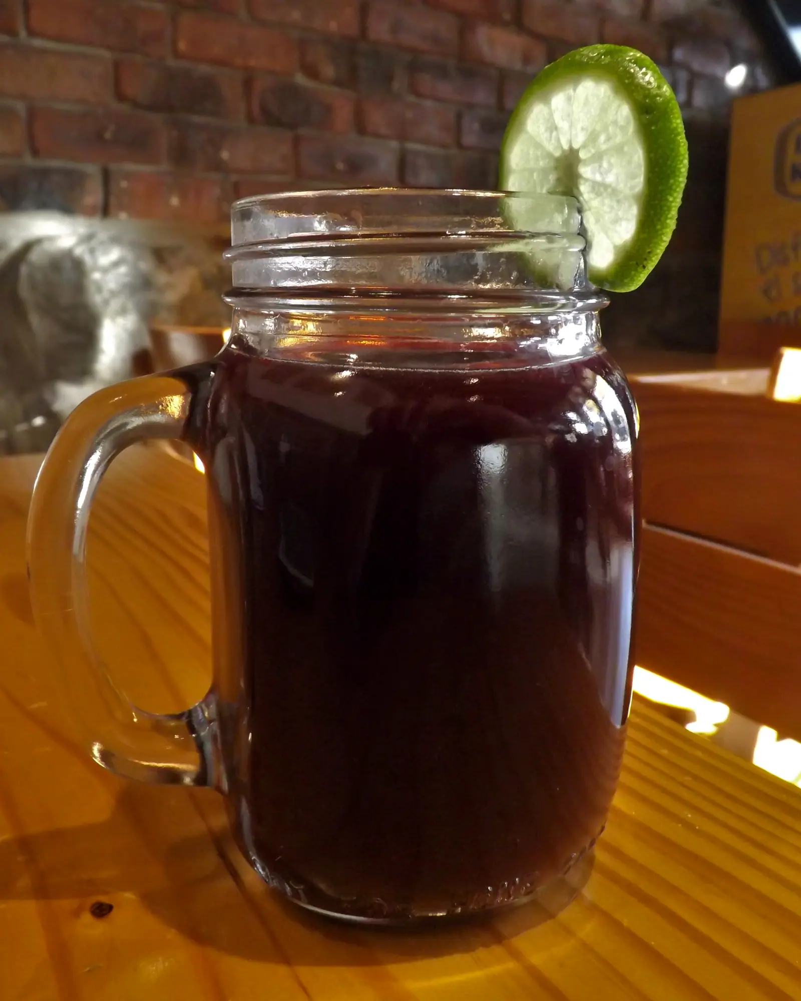 Deep purple chicha morada in a mason-jar mug, garnished with a lime wheel