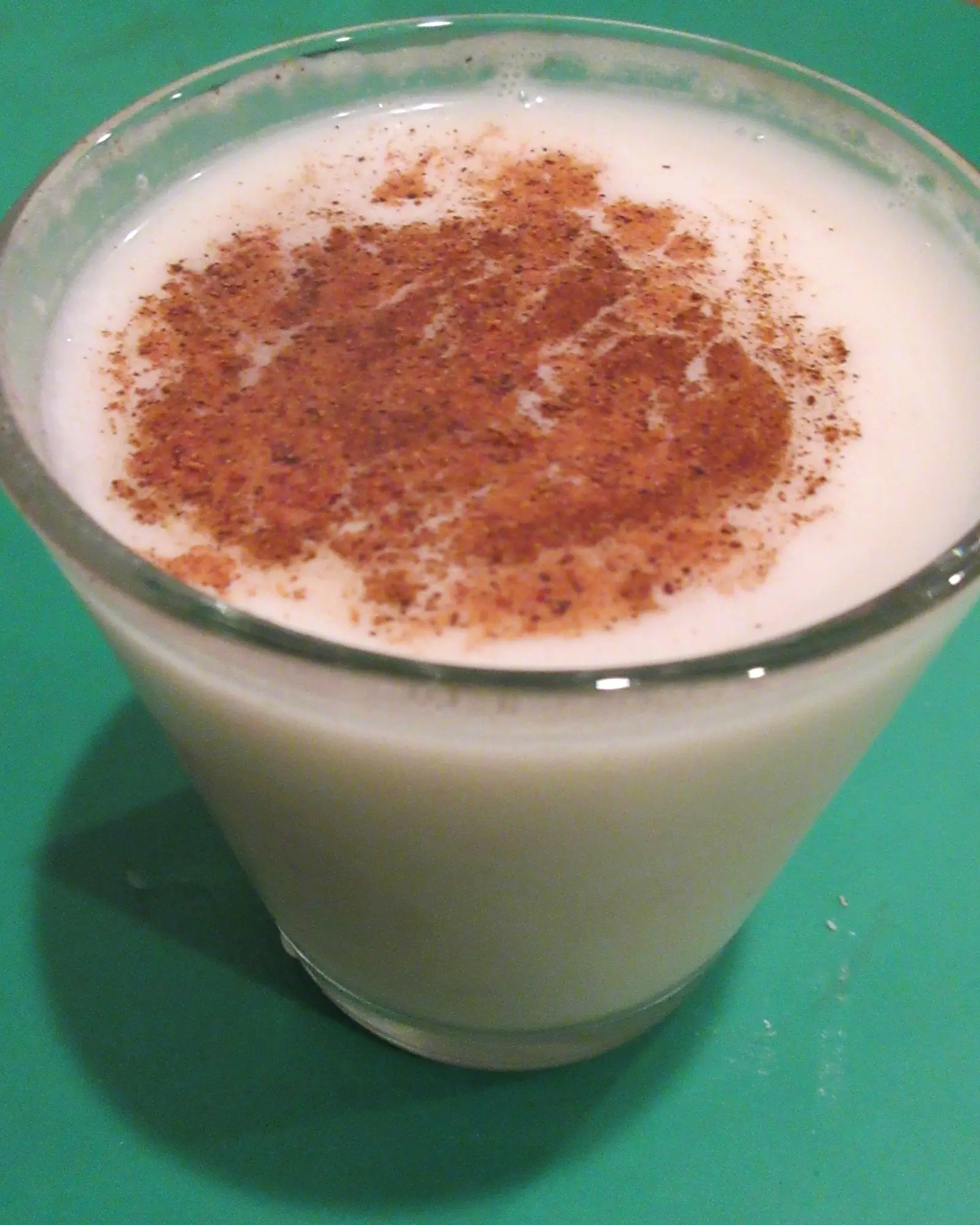 Creamy white coquito in a glass, dusted with ground cinnamon