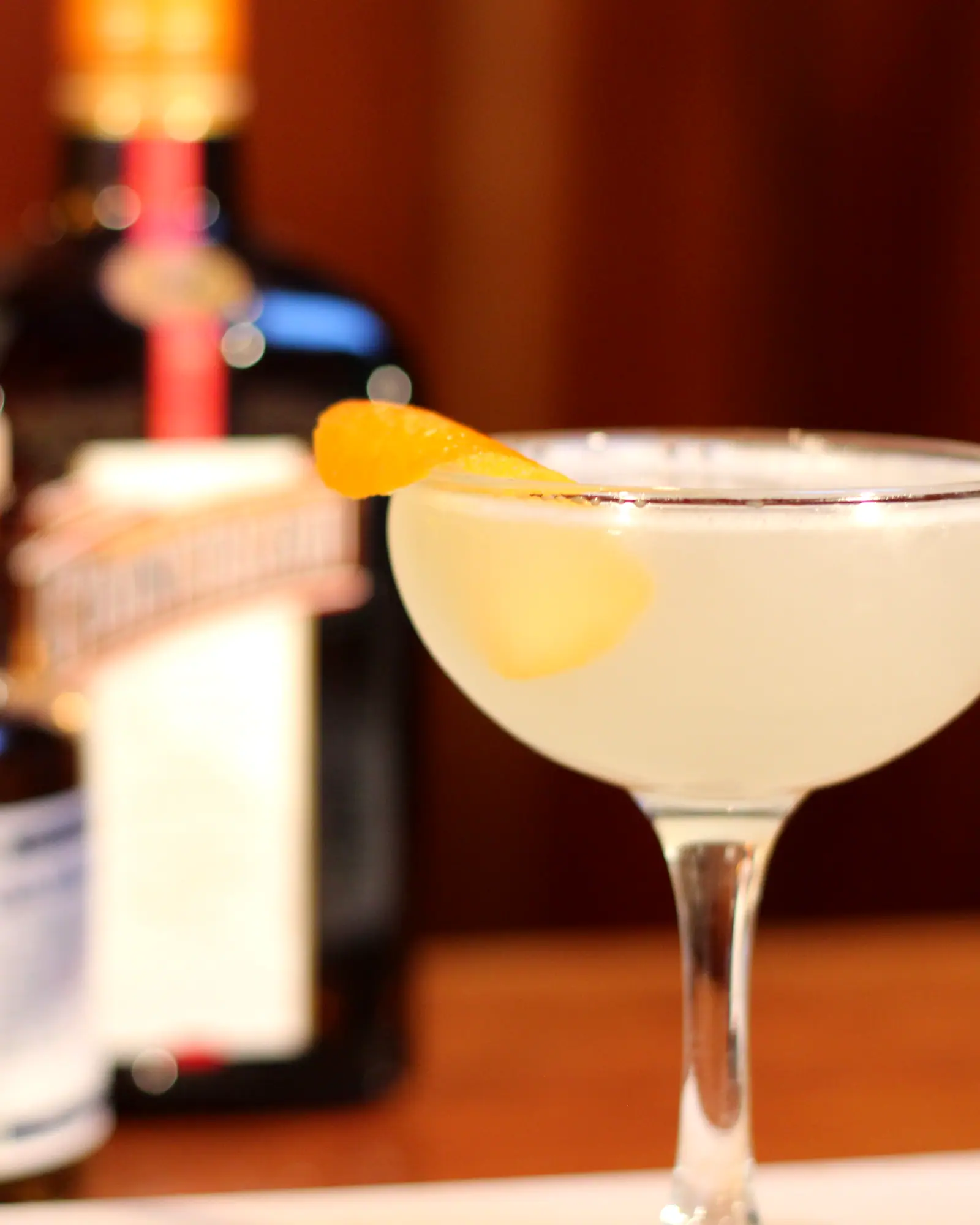 A Corpse Reviver No. 2 served up in a coupe with a lemon twist garnish, pale and clear