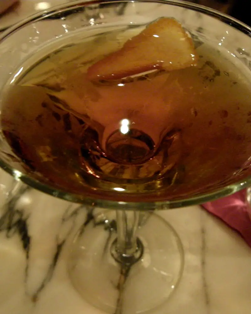 A Hanky Panky in a coupe glass, amber-orange with an orange peel garnish