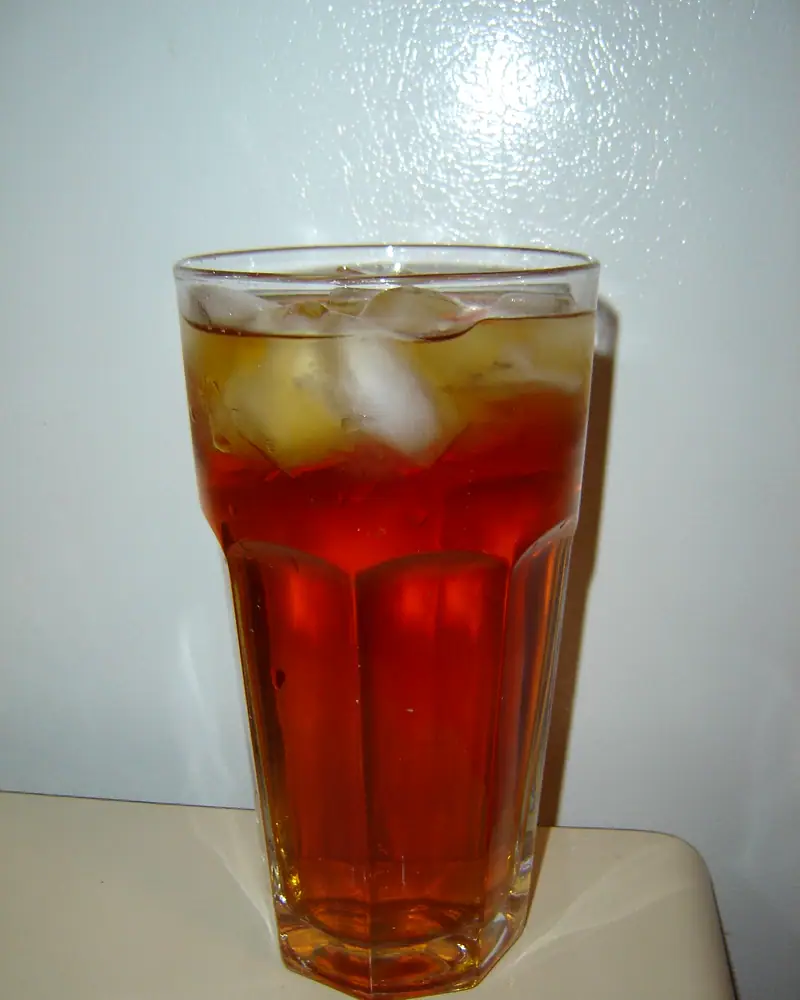 A tall glass of amber iced black tea over ice cubes