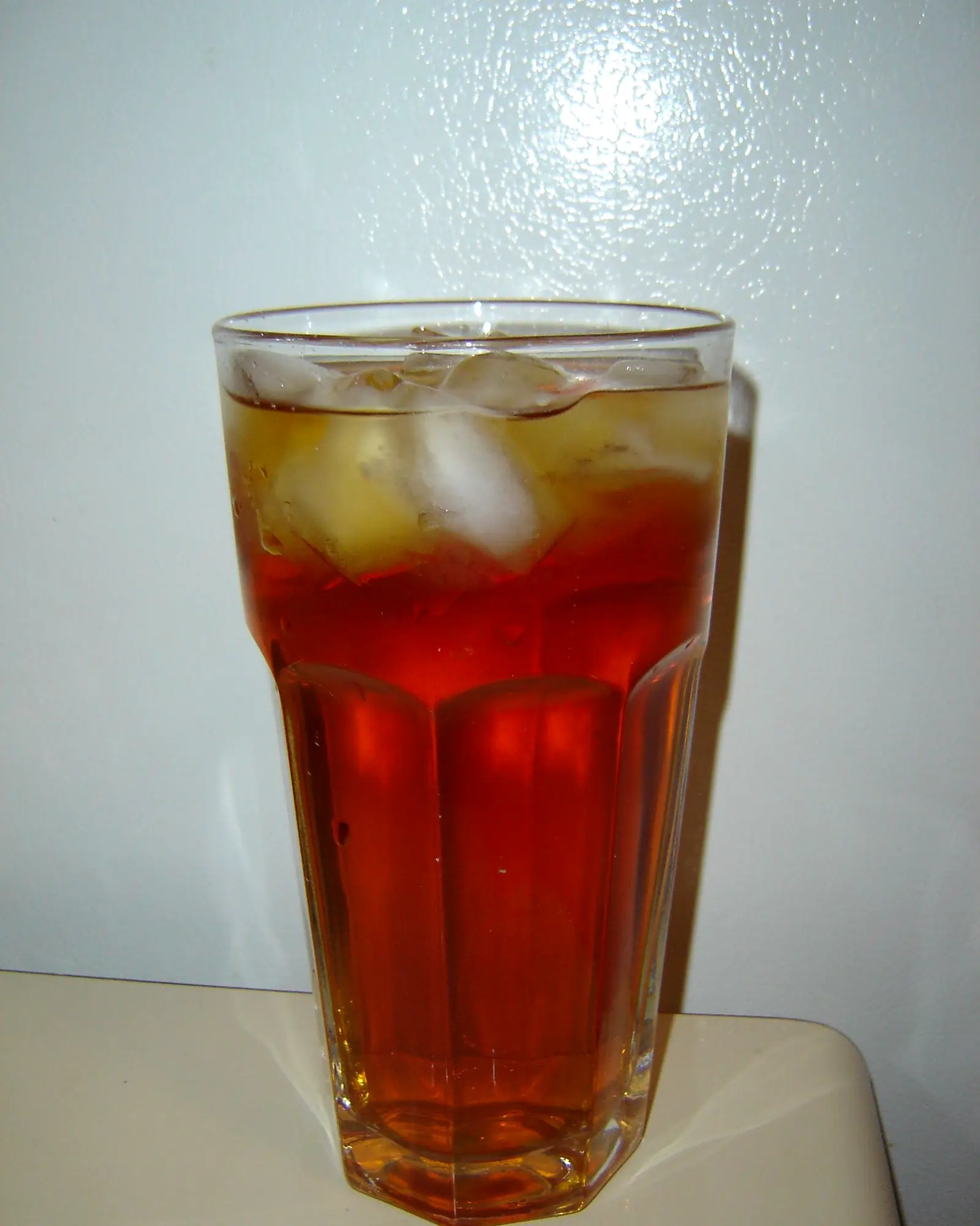 A tall glass of amber iced black tea over ice cubes