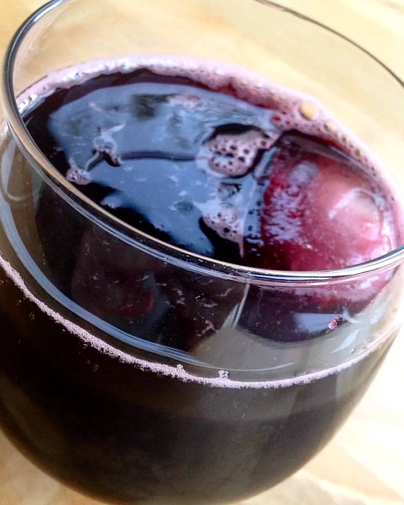 A dark red kalimotxo (red wine and cola) over ice cubes in a round glass