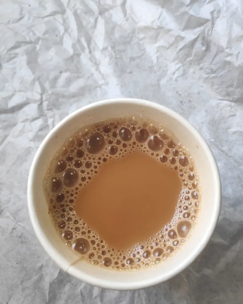 A cup of milky, foam-topped karak chai, viewed from above