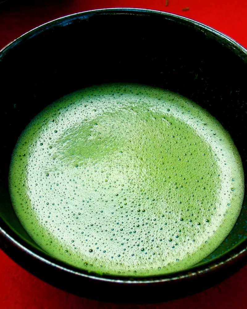 Overhead view of whisked usucha matcha in a black chawan, bright green with a fine foam