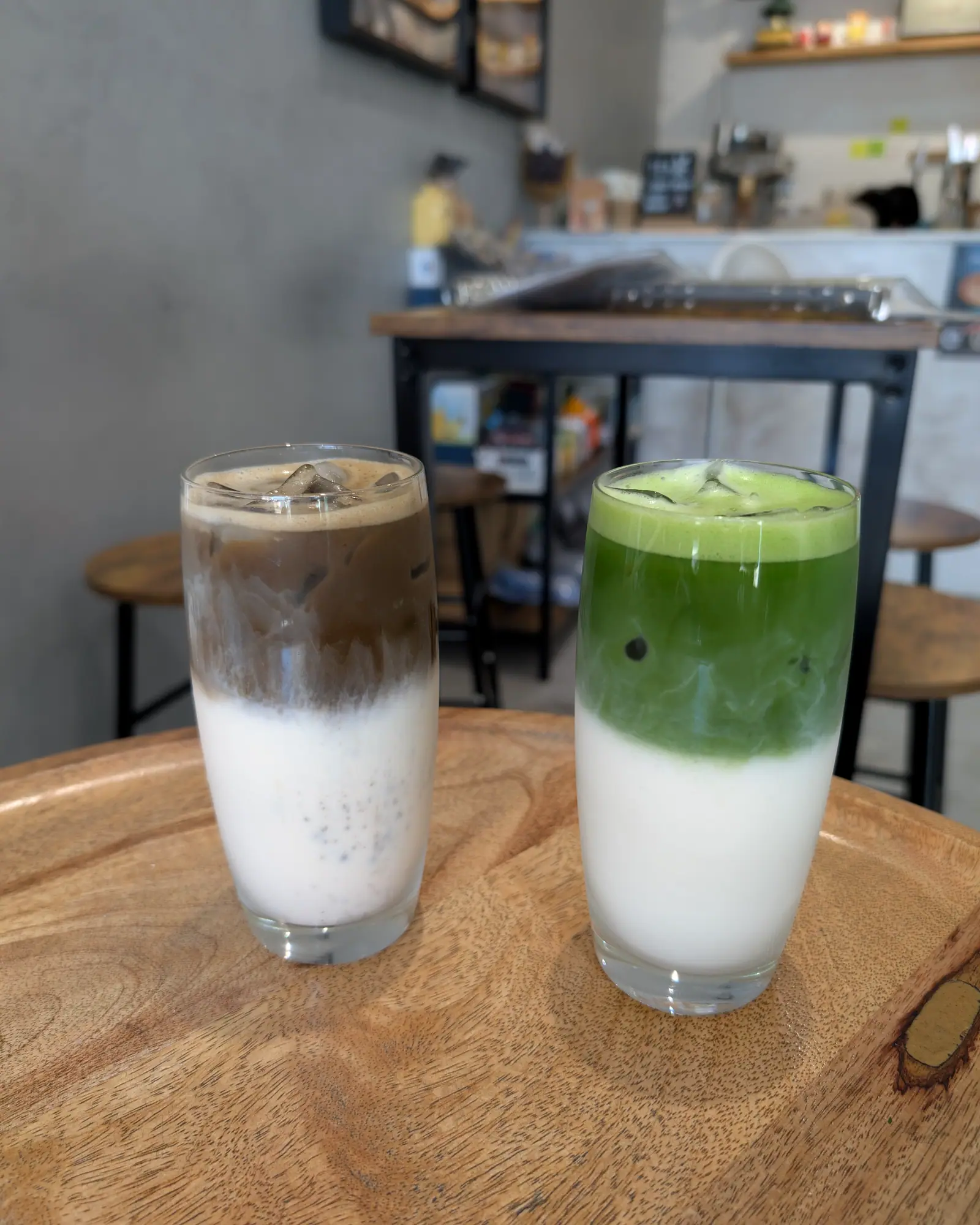An iced matcha latte in a tall glass, layered green matcha over white milk, beside another iced latte