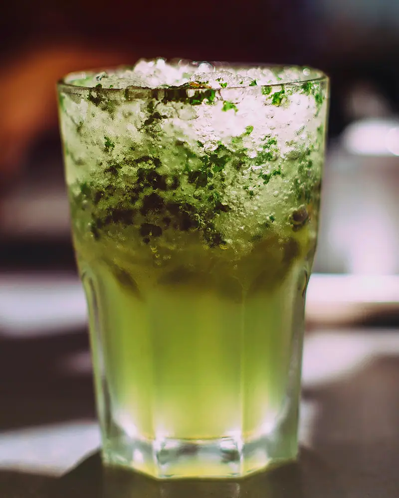 A Mojito in a tall glass topped with crushed ice and muddled mint