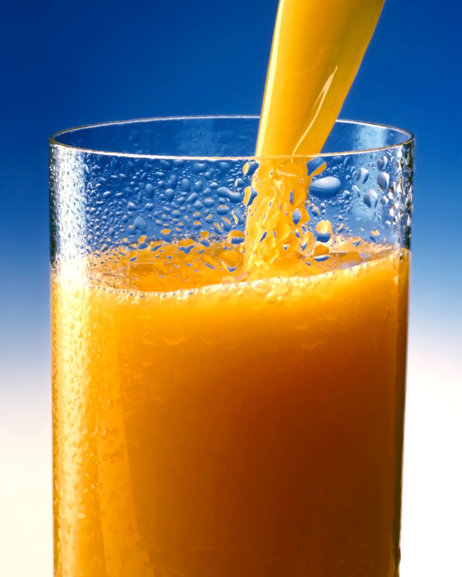 Orange juice being poured into a tall glass