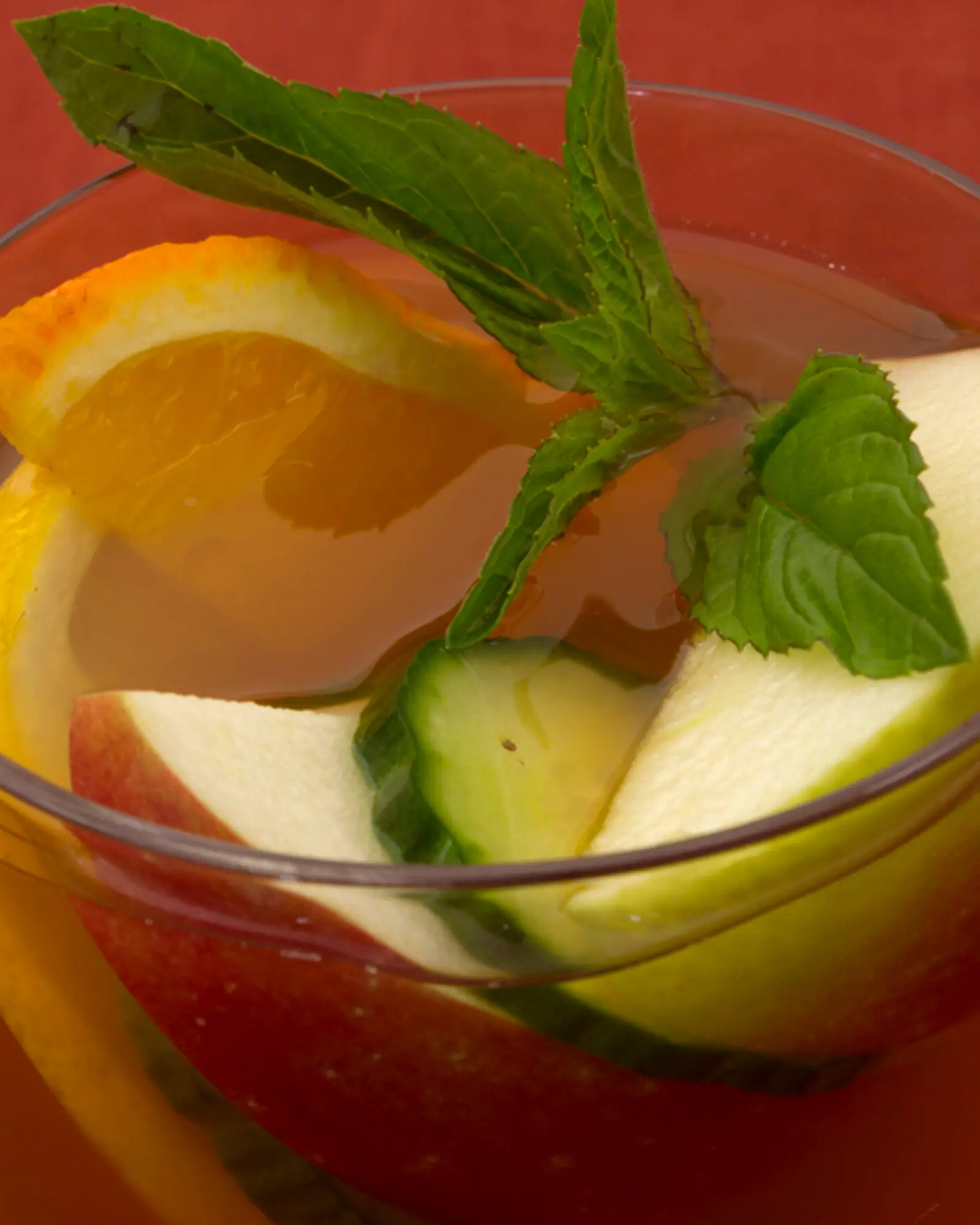Close overhead view of a Pimm's Cup with mint, cucumber, orange and apple pieces floating in the glass