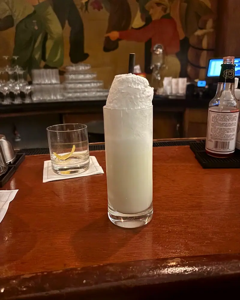 A Ramos Gin Fizz in a tall Collins glass, its dense white foam head standing well above the rim