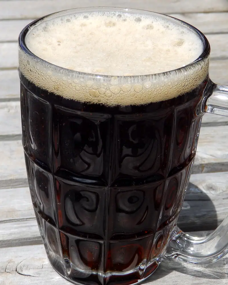 A mug of dark root beer with a thick foamy head
