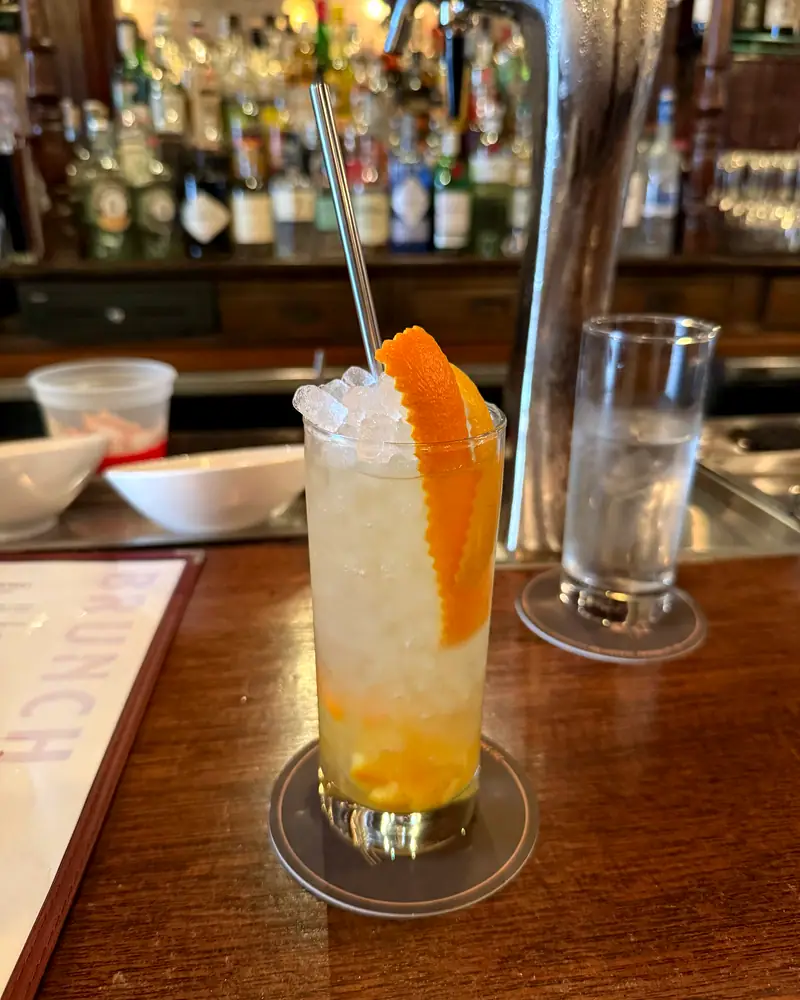 A Sherry Cobbler in a tall glass packed with crushed ice, garnished with a long curl of orange peel