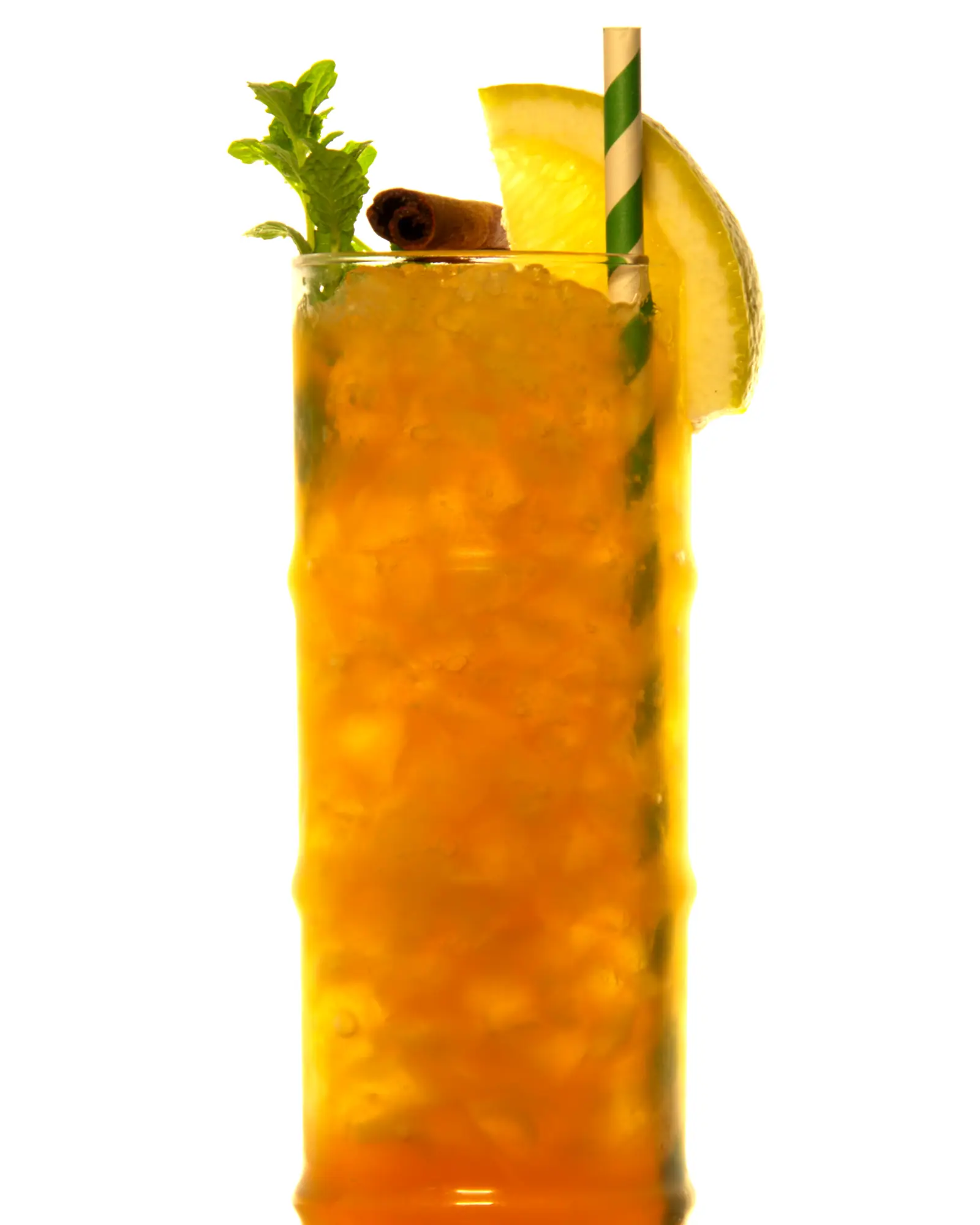 A Zombie in a tall collins glass packed with crushed ice, amber-orange, garnished with a mint sprig, cinnamon stick and orange wheel