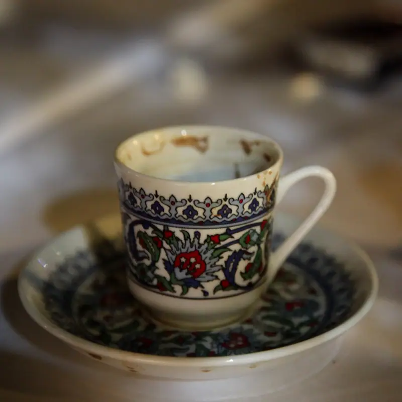 An empty small ornate handled coffee cup on a matching saucer