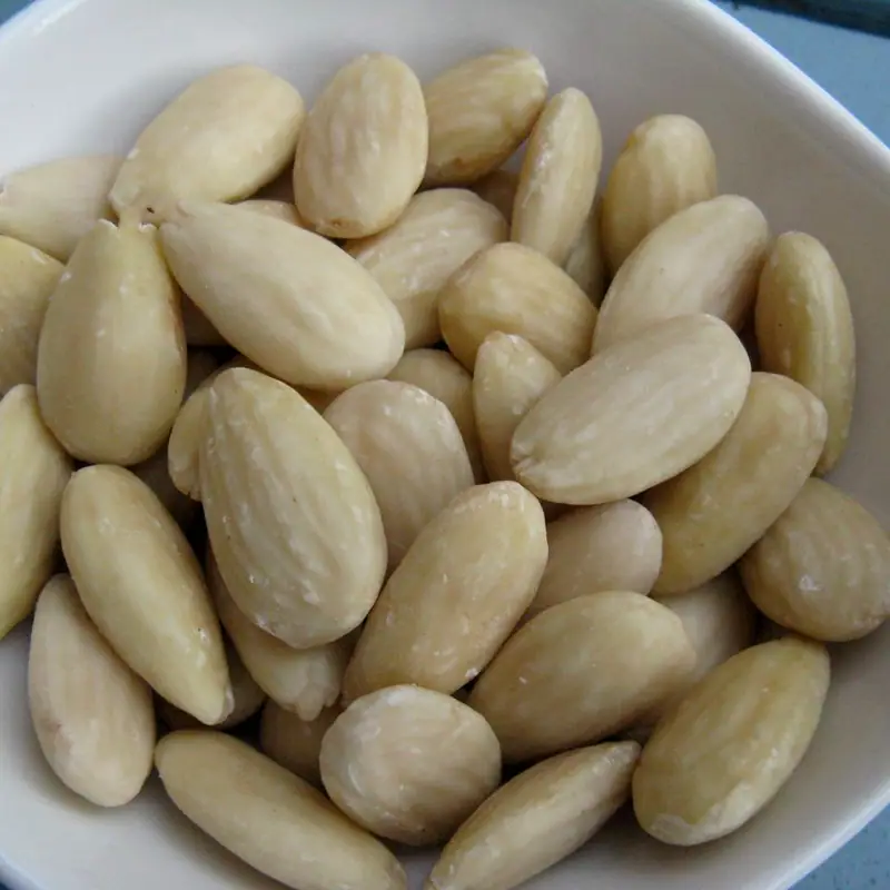 Blanched almonds, skinned and pale, heaped in a white dish