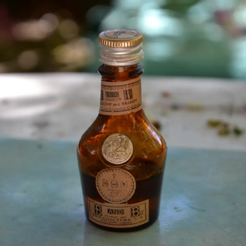 A small amber bottle of Bénédictine liqueur with its gold cap and label