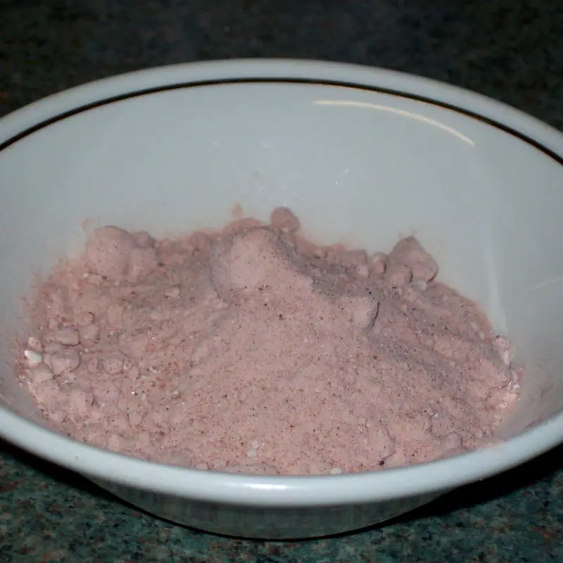 A bowl of ground black salt (kala namak), a fine pinkish-grey powder