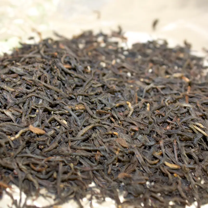 A close-up pile of loose, dark-brown black tea leaves