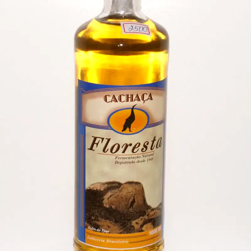 A bottle of golden cachaça labelled Floresta, on a plain background