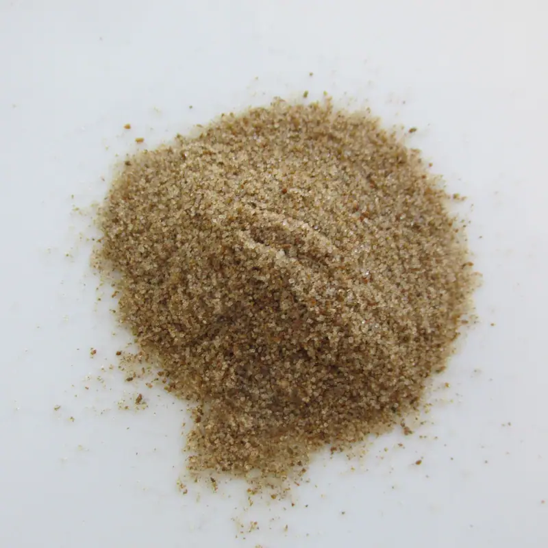 A small pile of coarse tan celery salt granules on a white surface