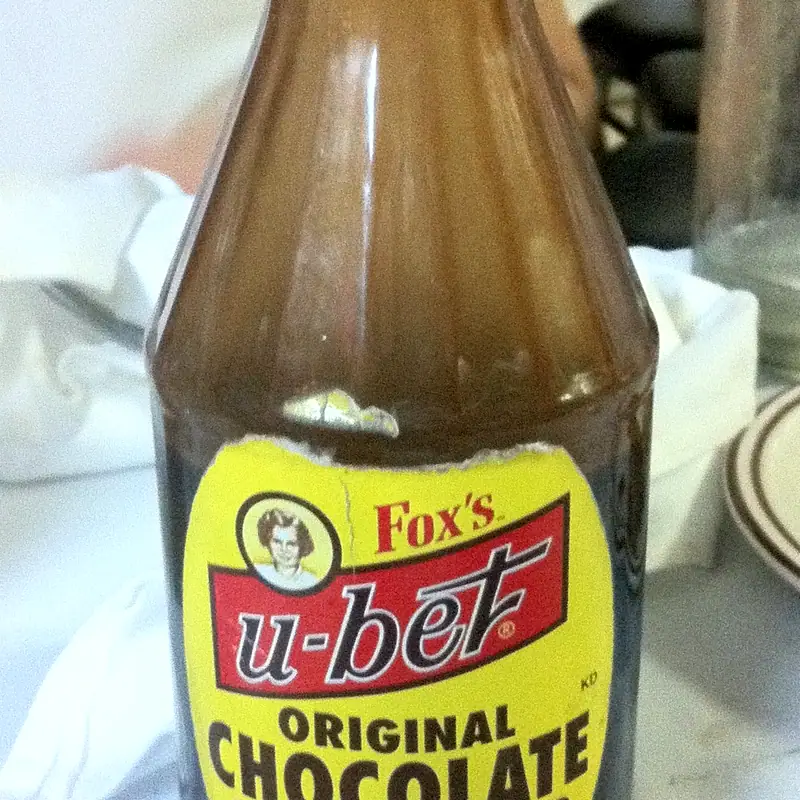 A glass bottle of Fox's U-Bet Original Chocolate flavor syrup, dark syrup visible through the glass