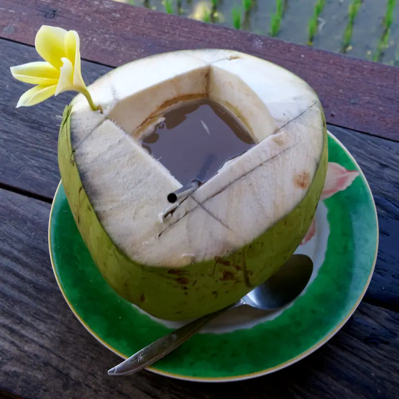 A young coconut sliced open at the top, showing the clear water inside