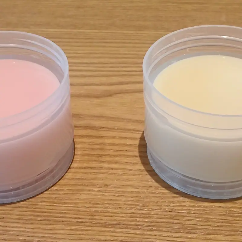 Two small tubs of condensed milk, one strawberry-tinted pink and one plain white