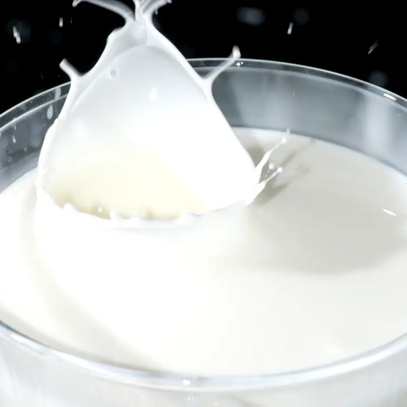 A close-up of a drop of cream splashing into a bowl of cream