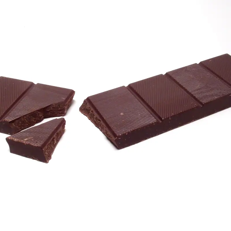 A broken bar of dark chocolate, unbranded, showing squares and rough fracture