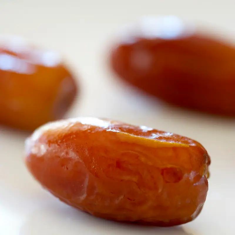 A close-up of glossy brown dried date fruits