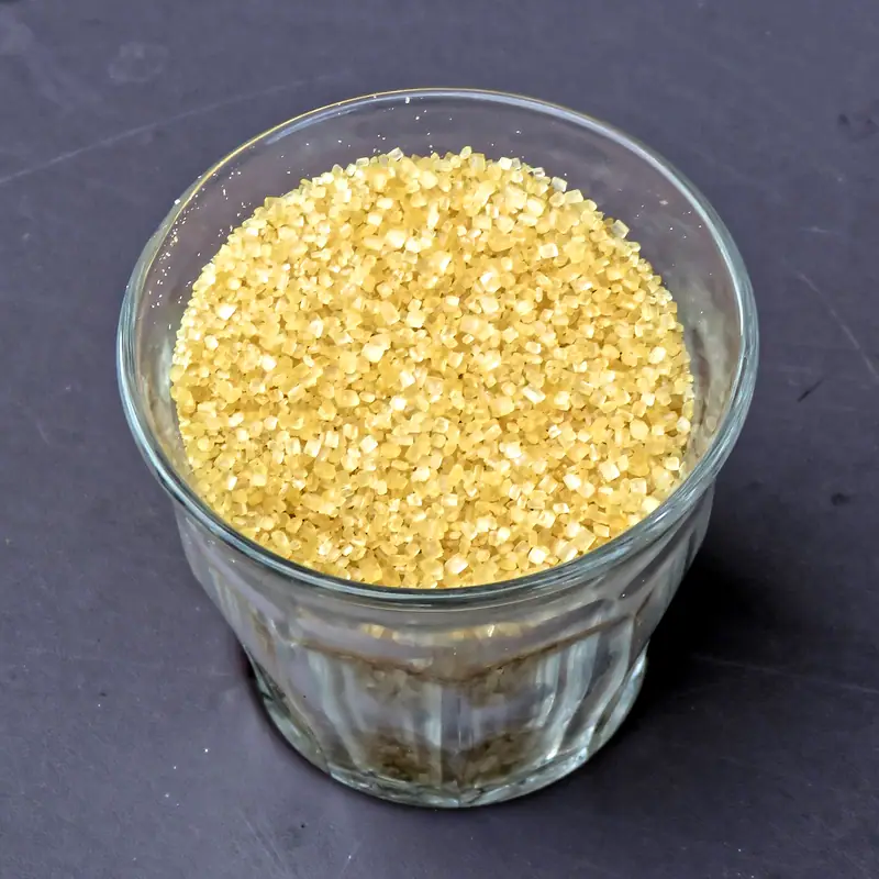 Coarse pale gold demerara sugar crystals in a small glass bowl