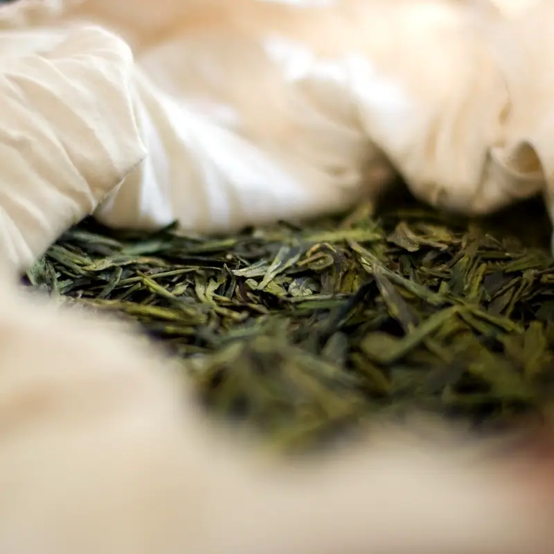Flat dried green tea leaves in a loose pile