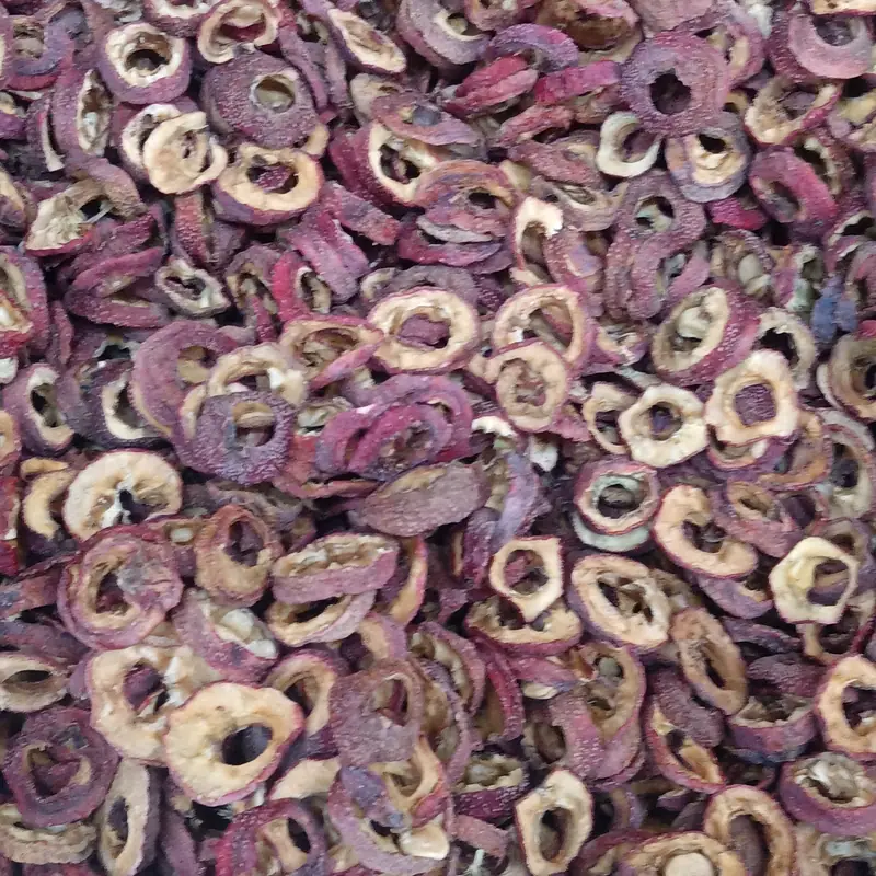 A close pile of dried hawthorn fruit rings, dark red-brown sliced fruit with hollow cores
