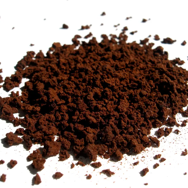 A pile of dark brown instant coffee granules on white