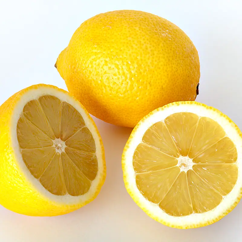 A whole lemon beside two halves showing its juicy yellow flesh