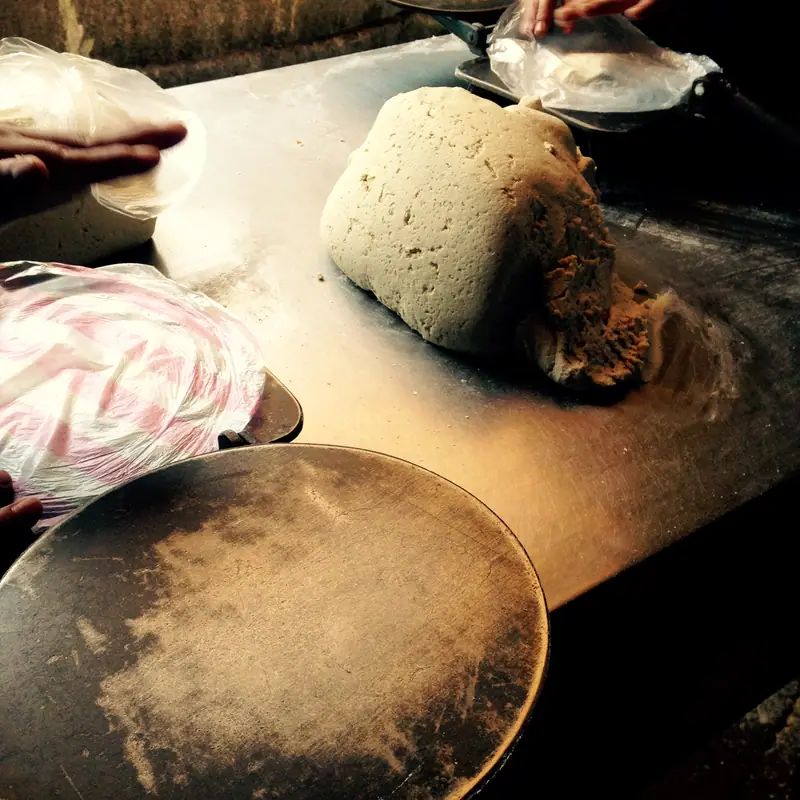 A lump of pale corn masa dough on a wooden surface, ready for pressing