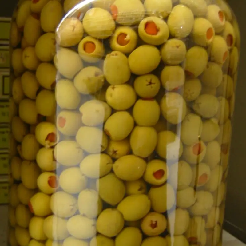 A large jar densely packed with pimento-stuffed green olives in brine