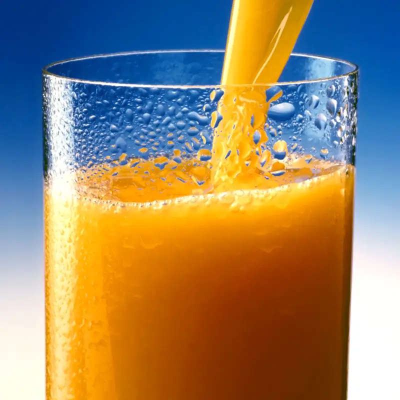 Orange juice pouring into a tall glass