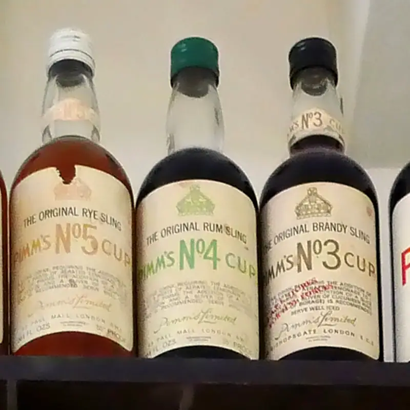 A row of vintage Pimm's Cup bottles, labelled No.5, No.4 and No.3