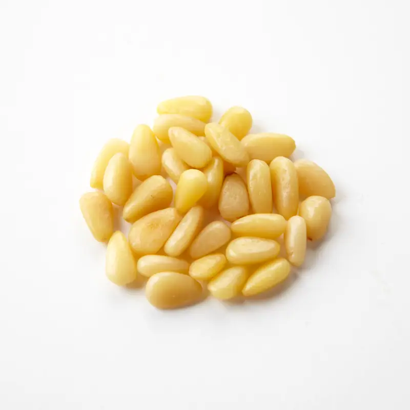 A pile of shelled pale yellow pine nuts on white
